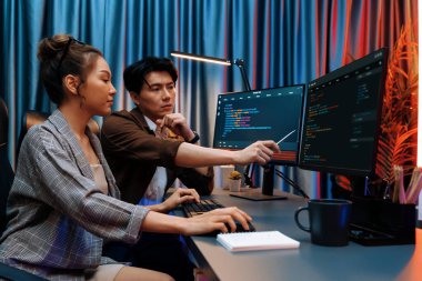 Bilgi teknolojisi geliştiricileri modern ofisteki neon ışık odasında verileri çevrimiçi olarak çalıştıran akıllı web sitesi geliştirme kodlayıcı sistemine işaret ediyorlar. İnfobahn.