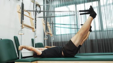 Bir grup müşteri, çekirdek dayanıklılığını ve bacak bağını geliştirmek için Cadillac reformatör makinesinde pilates egzersizleri yapıyor. Sağlıklı müşterilerin daha düşük poz verip kaldırma pozlarının üst görüntüsü. Sağlıklılık. Alışkanlık.