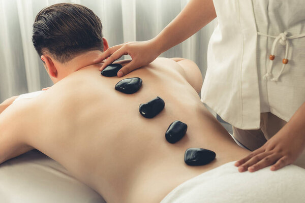 Массаж горячими камнями в спа-салоне на роскошном курорте с дневной легкой атмосферой спокойствия, блаженный клиент, наслаждающийся спа-массажем из базальтового камня скользит по телу с успокаивающим теплом. Quiescent