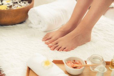 Panorama üstteki kadın lüks spa salonunda mutlu bir ayak masajı yaparken, masör de hafif gündüz atmosfer tesisinde veya otel ayak spasında refleksoloji terapisi uyguluyor. Sessiz.