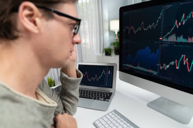 Bilgisayar ve dizüstü bilgisayarı kullanarak, çalışma masasındaki dinamik artırılmış borsa grafiğinin en yüksek kar değerini araştıran bir tüccar, modern ofisteki ekrandaki döviz kuru değerini analiz ediyor. Bireysel.