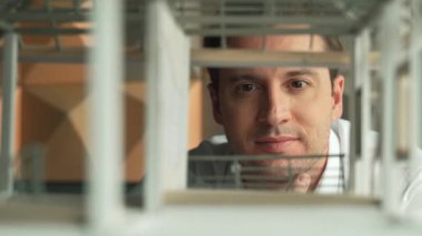 Kafkasyalı mimar mühendisinin yakın çekimi ev inşaatını denetlemek ve bina malzemelerini kontrol etmek. Proje yöneticisi modele dikkatlice bakarken kalemi işaret ediyor. Yönlendirici.