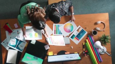 Tasarımcı yazma fikri ekrana bakarken proje yöneticisinin üst görünümü. Akıllı iş adamlarını kapat ve tasarımcı palete bakarken logo tasarımı fikrini açıkla. Sempozyum.