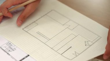 Akıllı mimar ya da akıllı mühendisin ölçüm aracı ve kalem el kullanarak mimari ofisindeki inşaat isabet planı üzerine detaylı bir yazı yazışının videosu. Eline odaklan. - Yakın çekim. Tanımlama.