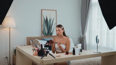 Sosyal medya için güzellik ve kozmetik video içeriği hazırlayan genç bir kadın. Güzellik blogcusu kameraya gülümserken seyircilere ve takipçilere güzellik bakımını gösteriyor. Düzenle