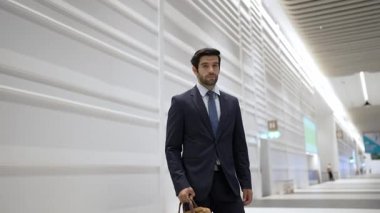 Beyaz arka planda dururken kameraya bakan bir iş adamı. İş elbisesi giyerken kameraya gülümseyen başarılı adamın yakın çekimi. Yönetici, kameraya bak. Hareket eden kamera. Sevinçli..