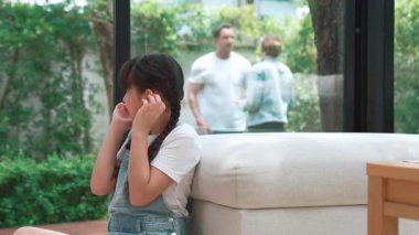 Stresli ve mutsuz genç kız köşeye kıvrılıp kulaklarını kapatarak arka planda ebeveyninin tartışmasını engelliyor. Evde aile içi şiddet ve travmatik çocukluk depresyona dönüşür. Titiz