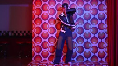 Asyalı break dansçı serbest stile geçiyor ve balon arka planlı kameraya bakıyor. Profesyonel hippi gündelik kıyafet giyer ve gözlük takar. Mutluluk.