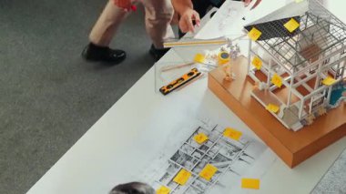 Profesyonel mimar mühendis ekibinin en iyi görüntüsü ev modelini incelerken, yöneticinin elinde bina inşaatı hakkında sorular sorması. Çeşitli mühendislerden oluşan bir grup birlikte çalışıyor. Hizalama.