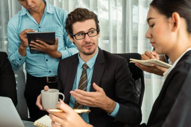 Modern ofis ortamında çalışan çeşitli etnik gruplardan çeşitli iş adamları. Üretken ve çok ırklı ofis çalışanları stratejik ticari pazarlama konusunda tartışmaya giriştiler. Habiliment