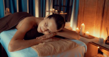 Beyaz kadın müşteri stres önleyici spa masajının keyfini çıkarıyor ve lüks otel ya da otelde sıcak mum ışığında güzellik teniyle eğleniyor. Sessiz.