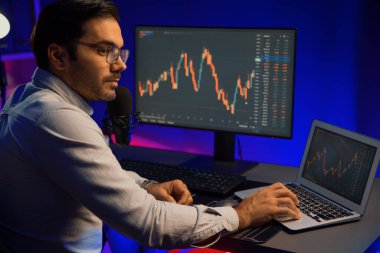 Akıllı tüccar işadamı, karanlık oda gecesinde neon ışıklı ofisteki arama pazarında yüksek kârla ekranda bilgisayar ve bilgisayar üzerinde dinamik borsa yatırımları üzerinde yoğunlaşıyor. Tahmin et..