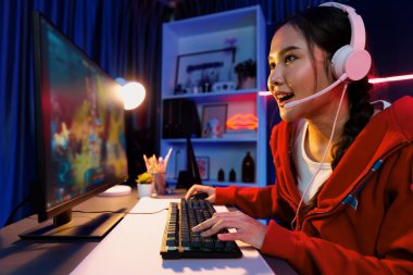 Genç ve güzel Asyalı oyun flamasının sunucu kanalı Moba ile savaş arenasında çoklu oyunlarla oyun oynuyor, neon dijital ışık modern odasında pastel kulaklık takıyor. Taktik.