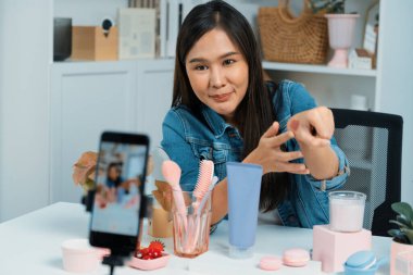 Genç, güzel Asyalı kozmetik makyaj ruju matte pastel rengini modern odadaki sosyal medyada kol testi tanıtımında en çok satanlar listesinde gösteriyor. Taktik.