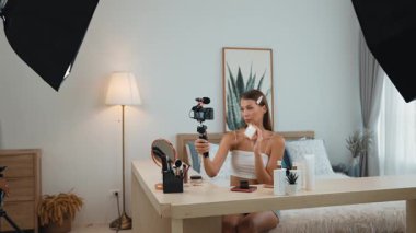 Sosyal medya için güzellik ve kozmetik video içeriği hazırlayan genç bir kadın. Güzellik blogcusu kameraya gülümserken seyircilere ve takipçilere güzellik bakımını gösteriyor. Düzenle