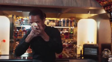 Asyalı akıllı barmen karışık kokteyl sallayarak lüks tezgah hazırlıklarına hazırlanıyor, kameranın önüne bakarak özel bir içecek hazırlıyor. Özel gece hayatı lüksü. Vinosity.