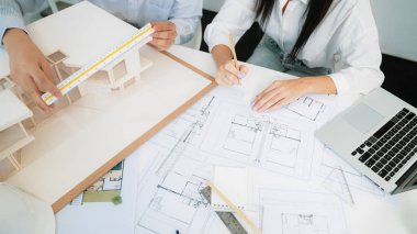 Profesyonel mühendis ev modelini tartartarken, yetenekli tasarımcı da planına yazar. Birlikte çalışmak, işbirliği, işbirliği. Yaratıcı tasarım ve takım çalışması konsepti. - Yakın çekim. Tertemiz.