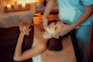 Beyaz kadın stres önleyici kafa masajı yapmaktan ve lüks otel veya otelde sıcak mum ışığında yüz güzelliği eğlencesi yapmaktan zevk alıyor. Sessiz.