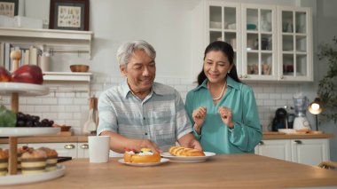 Büyükannem kahvaltısını sunarken, gülümseyen büyükbaba masada oturuyor. Yaşlı çift konuşuyor ve birlikte vakit geçiriyorlar ya da birlikte destek oluyorlar. Sağlıklı ilişki kavramı. Myrmidon.