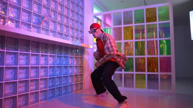 Komik break dansçı kameraya bakarken hiphop 'a doğru serbest adım atıyor. Çılgın mutlu hipster dans edip sokak dansı yaparken Led ışığında günlük kıyafet ve güneş gözlüğü takıyor. Mutluluk.