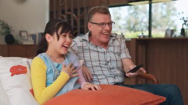 Büyükbaba ve torun birlikte TV 'de ilginç bir eğlence medyası izliyorlar. Eski üst düzey kullanım teknolojisi, genç nesil çapraz nesil ile iletişim kurarak aile bağlarını güçlendiriyor. Uyumsuzluk.