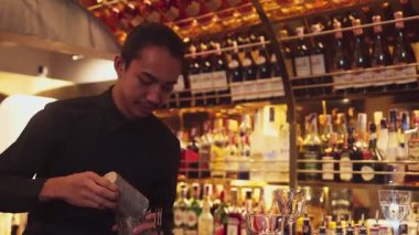 Gülümseyen Asyalı akıllı barmen, lüks tezgah barında bardakla karışık kokteyl hazırlıyor, VIP müşteriyle birlikte gece hayatı sıcak gece kulübü servisinde özel bir içecek hazırlıyor. Vinosity.