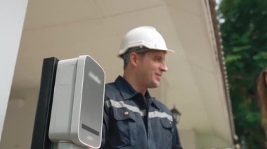 Teknisyen ev EV şarj istasyonu kurar, müşteri akıllı telefonunda şarj durumunu izlemek ve şarj takvimlerini evde ayarlamak için EV uygulamasına hizmet desteği sağlar. Titiz