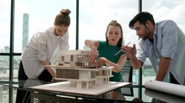 Beyaz proje yöneticisi dizüstü bilgisayar analiz verilerini kullanırken, mimar mühendis ekibi ev modeli inşaatını analiz etmek için birlikte çalışıyor. Bir grup tasarımcı ev tasarımı hakkında konuşuyor. İzleme