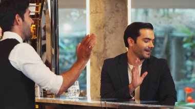 Tezgahta oturup barmenle konuşan zeki müşteriler gece kulübü lüksünde içki listesi tavsiye eden profesyonel barmen kostümü için harika bir izlenim bırakıyorlar. Vinosity.