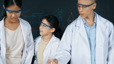 Zeki kız deney yapmak için heyecanlanan çeşitli öğrenciler iken beher kabına renkli solüsyon döker. Profesyonel bilim adamı kimyasal teoriyle kara tahtada deney yapmaya hazırlanıyor. Öğretim.