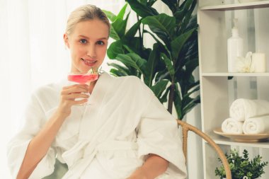 Güzellik ya da vücut bakımı güzellik salonu yaşam tarzı konsepti. Bornoz giyen bir kadın lüks otel kaplıcalarında ya da tatil odasında içkiyle rahatlıyor. Tatil ve boş zaman rahatlığı. Sessiz.