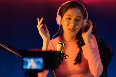 Yaratıcı yayın kanalı sosyal medyada pozitif podcasttaki dinleyicilerle birlikte müziği dinliyor, pastel renkli kulaklıklar takıyor, neon stüdyodaki kameraların mikrofon kayıtlarını kullanıyor. Taktik.