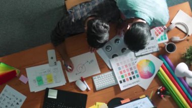 Akıllı tasarımcının renkli paletlerden renk seçmesine yardım ederken yukarıdan aşağı görünümü. Dizüstü bilgisayardan logoya bakarken birlikte çalışan ve planlayan iş adamlarının hava görüntüsü. Sempozyum.