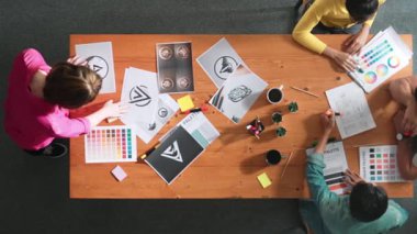 Proje yöneticisi renk paletleri seçerken tasarımcının tablete baktığı yukarıdan aşağıya hava görüntüsü. Profesyonel grafik tasarımının en üst görüntüsü ve logoya bakın. Yetenekli ekip grafikleri seçiyor. Sempozyum.