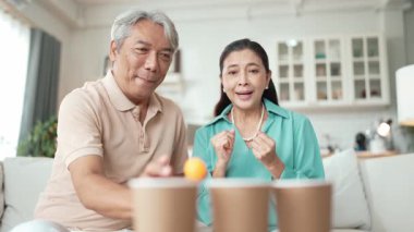 Mutlu yaşlı çift evde birlikte top atmaktan zevk alıyor, sağlıklı yaşlanma için koordinasyon ve bilişsel beceriler geliştiriyorlar. Büyükbabam ve büyükannem klozete pinpon oynuyorlar. Myrmidon.