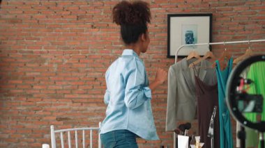 Kadın nüfuzlu kişi canlı yayında video görüntülerini çekiyor. Kıyafetler sosyal medya ya da blog için çok önemli. Stüdyo ışıklandırmalı mutlu genç kız çevrimiçi pazarlama oturumu yayını için..