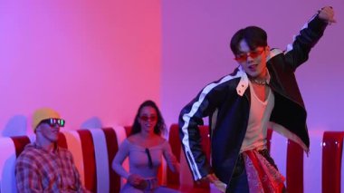 Asyalı bir adam pop müzikle dans ederken, çok kültürlü bir arkadaş evde ışık altında oturuyor. Çekici bir sokak dansçısı kameraya bakarken hip hop müzik dinliyor. Mutluluk.