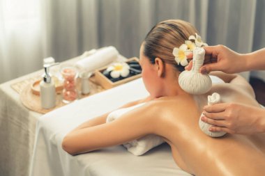 Sıcak bitkisel top spa masaj vücut tedavisi, masör kadın vücuduna nazikçe şifalı bitki torbası bastırıyor. Aromaterapi dinlenme sükuneti ve sükuneti kaplıca salonundaki atmosferi aydınlatıyor. Sessiz.