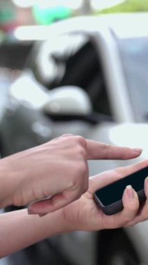 Modern iş kadını akıllı telefonun 3D hologramından batarya durumunu kontrol ederken EV arabasının şarj olan enerjisini kontrol eder. Gelecekteki EV otomotiv teknolojisinin yenilikçi teknolojik gelişimi. İnceleyin