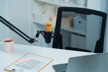 Beyaz masada duran tüm canlı yayın setleri dizüstü bilgisayar, mikrofon, kulaklık, ağaç, senaryo notu ve kalemden oluşur. Sosyal medyada canlı yayında sunucu kanalı için beklemedeyiz. Taktik.