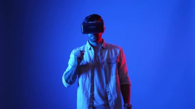 Sanal dünyada araba sürerken VR gözlük takan sıradan giysili profesyonel bir oyuncu. Erkek model yarış oyunu oynarken sanal gerçeklik kulaklığı kullanarak metadünyaya erişiyor. Aygıt.