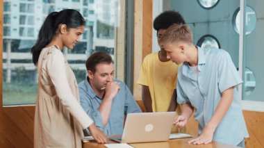 Lisedeki çocuk dizüstü bilgisayara bakarken proje sunuyor. Çeşitli öğrencilerden oluşan bir grup ayakta duruyor ve planı açıklarken akıllı eğitmen de dinliyor ve tavsiye veriyor. Takım çalışması konsepti. Öğretim