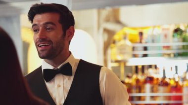 Güzel görünüşlü, zeki barmen dostu sohbet içecek tezgahında VIP müşteriyle konuşuyor. Profesyonel barmen kostümünde harika bir ilk izlenim bırakıyor. Vinosity.