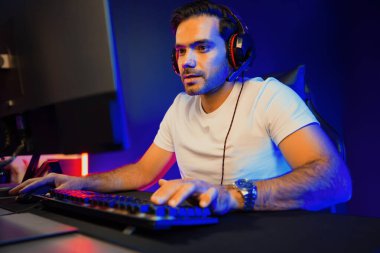 Akıllı oyun kurucusu, dijital neon ışıklandırma stüdyosundaki sosyal medya uygulamasında başkalarıyla iletişim kurmak için kulaklık ve mikrofon kullanan takım üyeleriyle konuşuyor. Tahmin et..