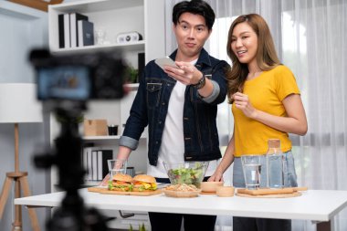 Aşçılar, sosyal medya yemek programı kanalı canlı yayın menü yemeği salatası, kepekli çörek ve video kameradan hamburger kaydı için telefonda yorum okuyorlar. İnfobahn.