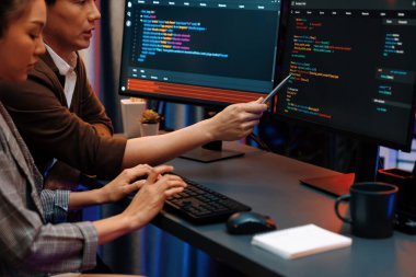 Bilgi teknolojisi geliştiricileri modern ofisteki neon ışık odasında verileri çevrimiçi olarak çalıştıran akıllı web sitesi geliştirme kodlayıcı sistemine işaret ediyorlar. İnfobahn.