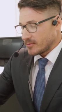 Ofiste çalışan kulaklık takan işadamları uzak müşteri ya da meslektaşlarını desteklemek için çalışıyorlar. Arama merkezi, tele pazarlama, müşteri destek acentesi telefon görüşmesinde hizmet sunar.