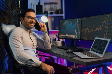 Tüccar akıllı iş adamı görünümlü kamera, broker ya da ortağı arıyor, neon ışıklı ofisteki bilgisayardaki dinamik borsa yatırımına karlı finans teknolojisi ile karşı karşıya. Tahmin et..