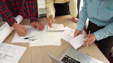 Mimarlık ve güvenlik mühendisi, modern ofiste doğruluk için mimari belge ve ölçüm aracı kullanılarak dizüstü bilgisayarın üzerinde sergilenen planlar hakkında tartıştı. - Yakın çekim. Tanımlama.