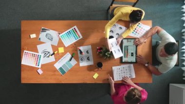 Proje yöneticisi renk paletleri seçerken tasarımcının tablete baktığı yukarıdan aşağıya hava görüntüsü. Profesyonel grafik tasarımının en üst görüntüsü ve logoya bakın. Yetenekli ekip grafikleri seçiyor. Sempozyum.